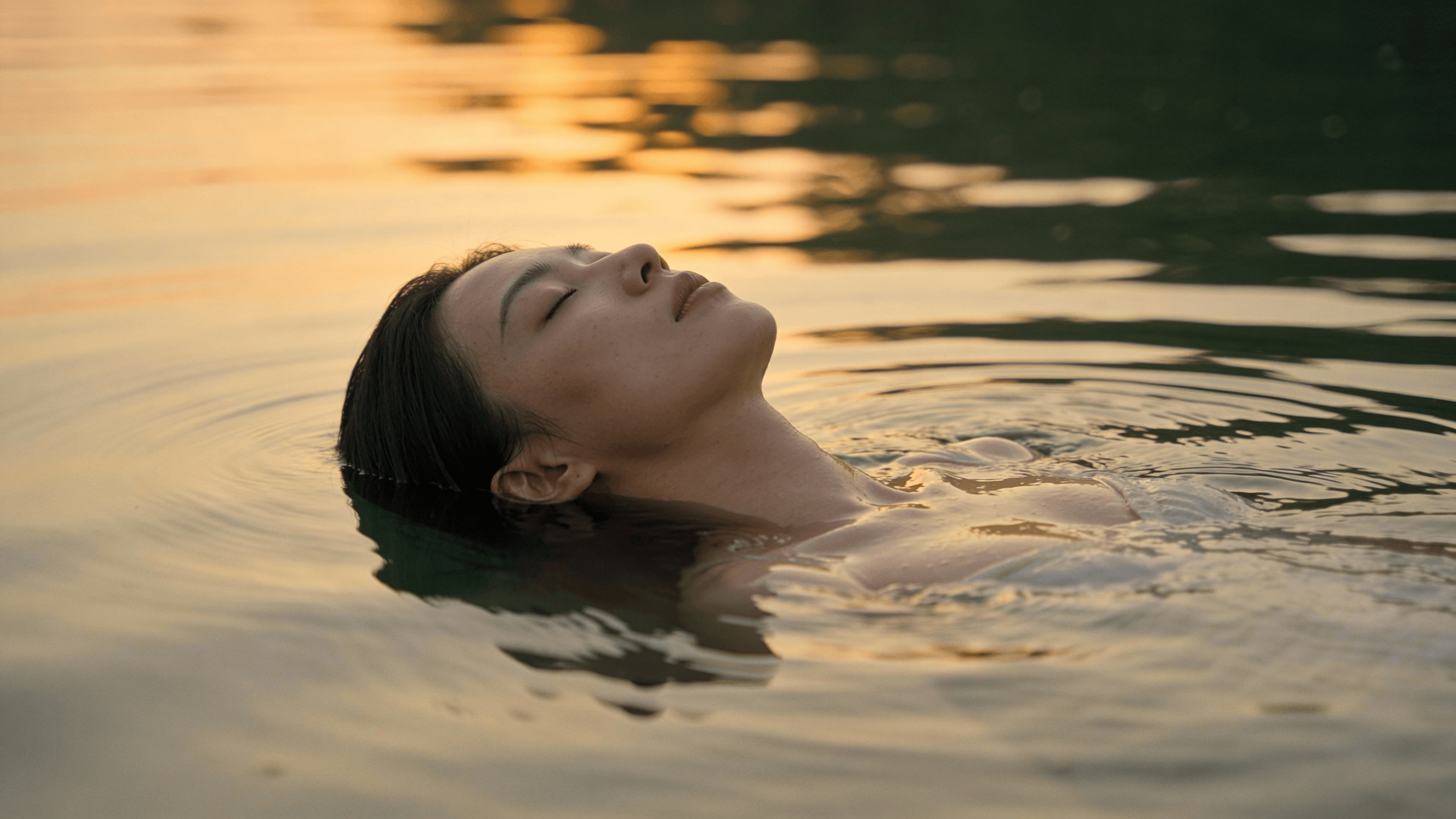Person floating peacefully in water at sunset